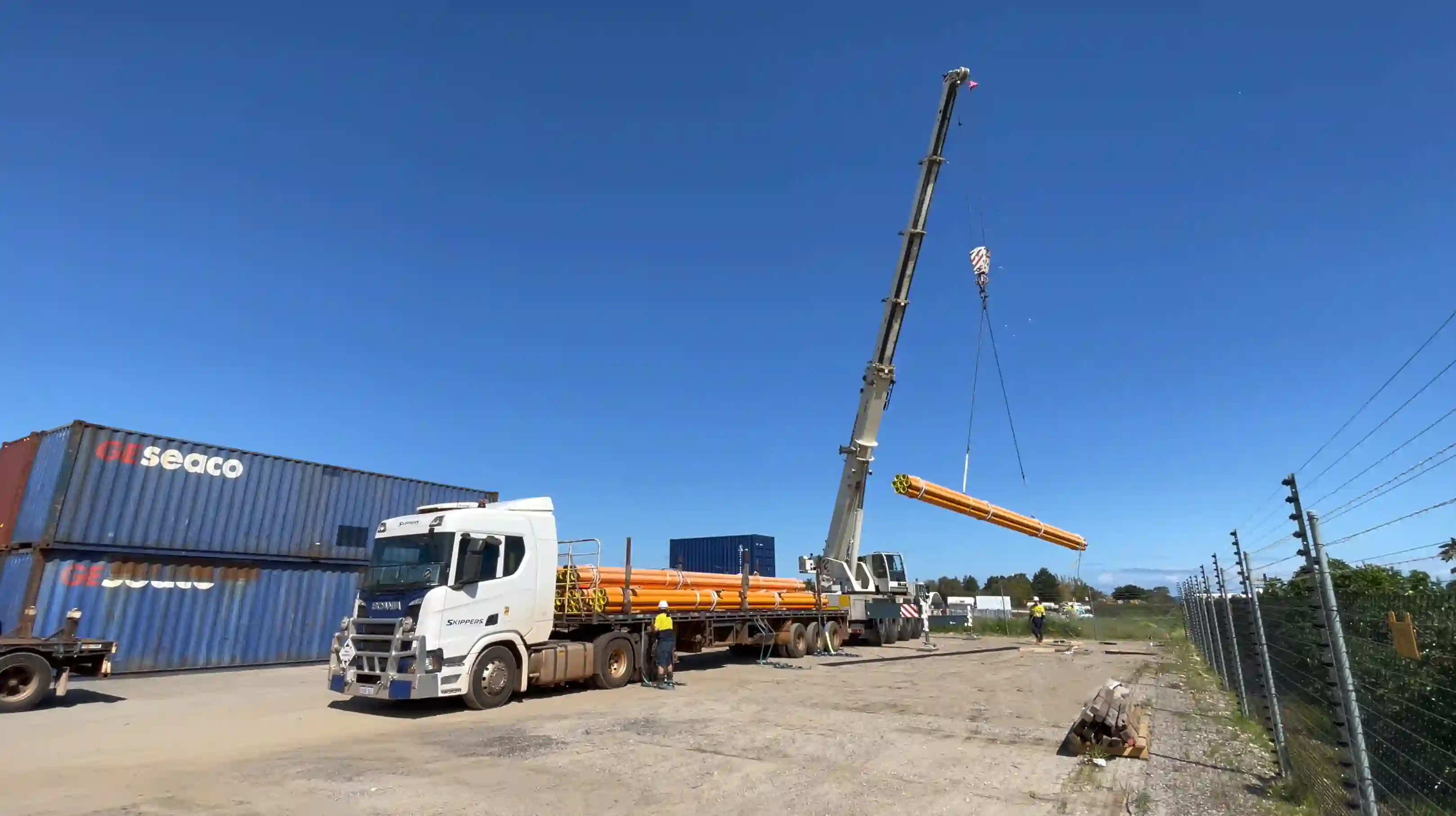 Skippers Transport truck with crane unloading large pipes at a logistics site in Perth, Western Australia.