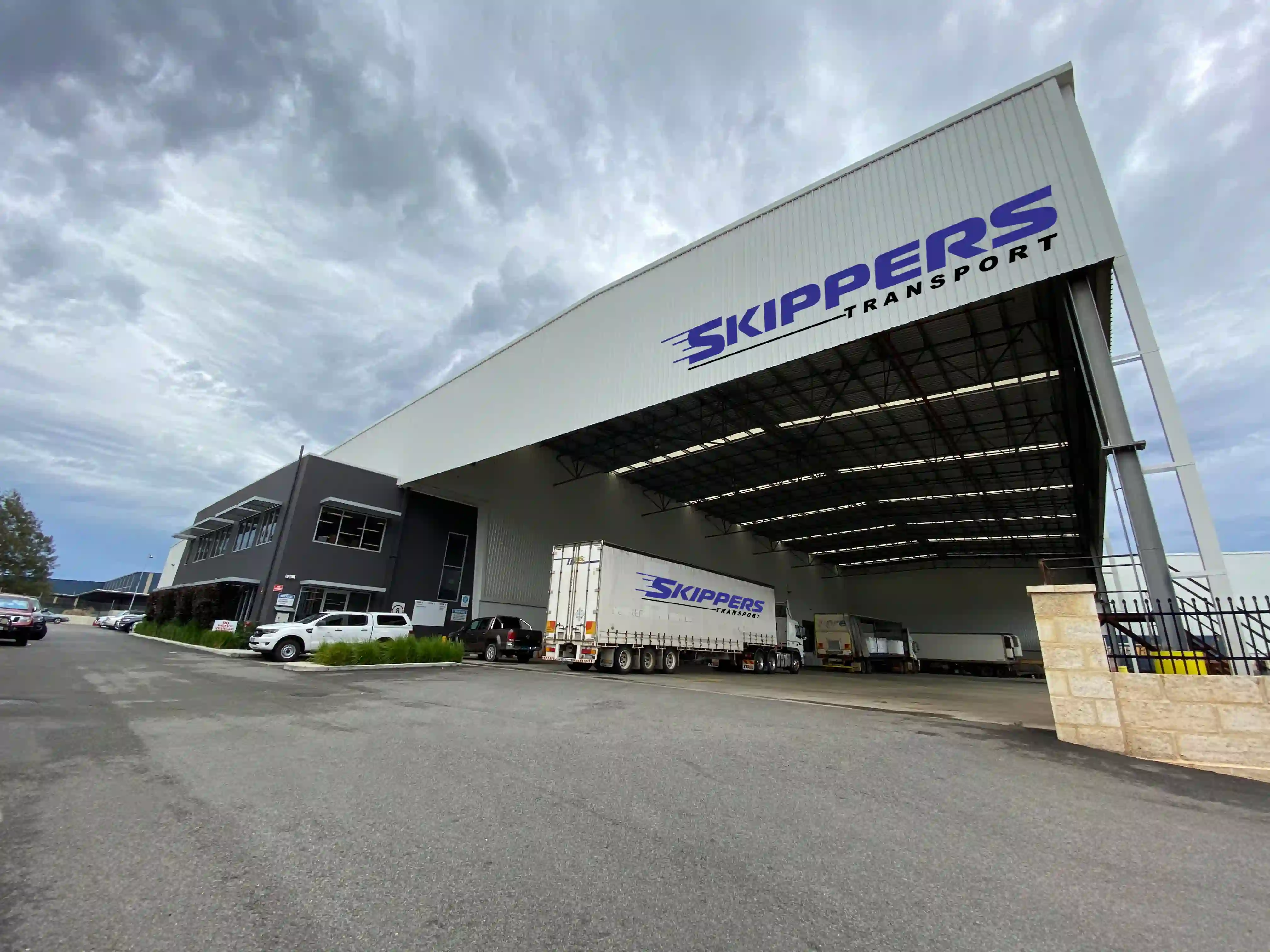 Skippers Transport warehouse facility with trucks and vehicles in front, showcasing their logistics and 3PL services in Perth, Western Australia